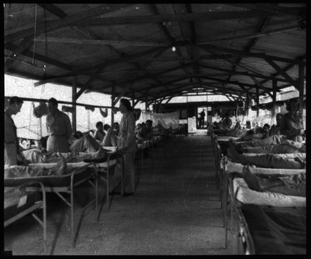 Interior view of typical medical ward. There is a utility building in background with another medical ward beyond