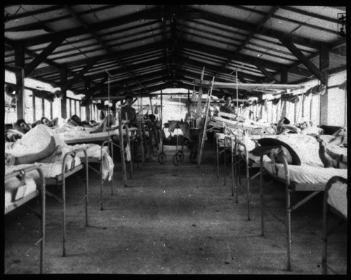 Interior view of typical orthopedic surgical ward, a row of beds occupied by people.