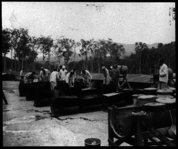 General view from office end of the Medical Supply Building. Note concrete platform and method of heating water in drums for washing mess kits and partitioned mess trays.